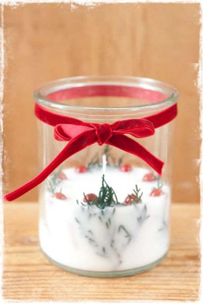 glazen pot met witte kaars en kerstgroen en rode besjes